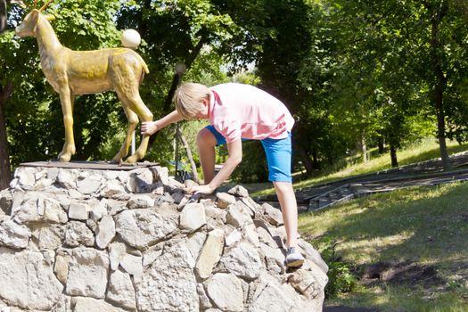 Smiling boy in pink shirt playing on stone wall