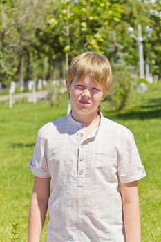 Portrait of dissatisfaction boy in white shirt outdoors