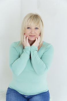 vertical portrait of blond woman with blue eyes in green