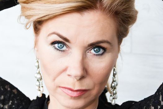 Horizontal portrait of blond woman with big pearl earrings on white background