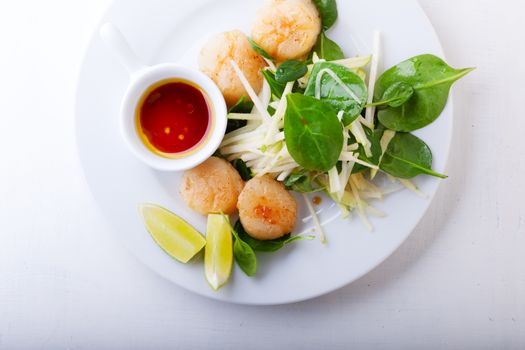 Scallop Salad with greenery served on a white plate