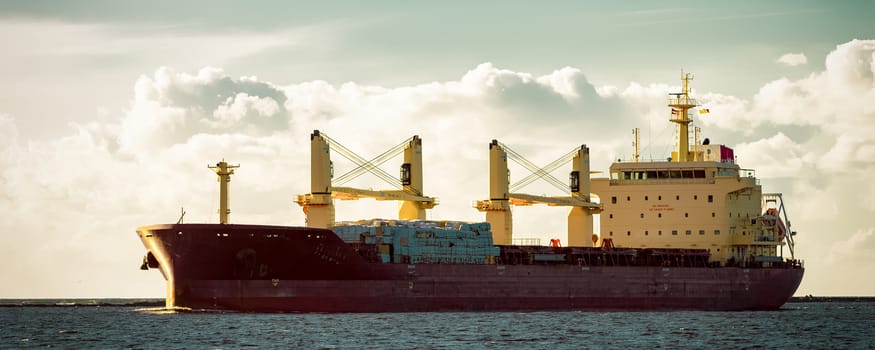 Red cargo ship moving entering the port of Riga