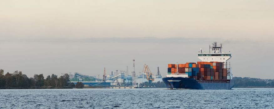 Blue container ship moving to Baltic sea. Riga, Latvia