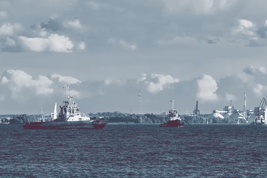 Two tug ships are accepting cargo vessel at Daugava river