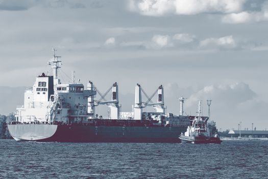 Cargo ship and the tug ship towing it to the port