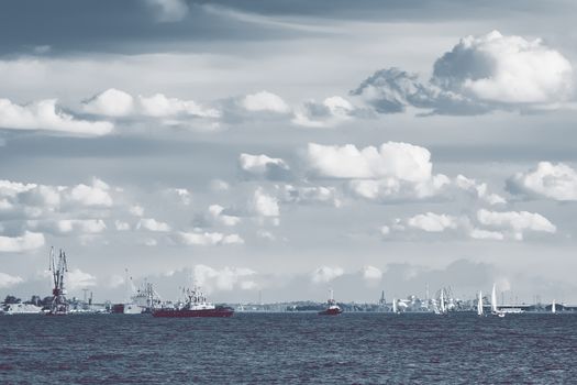 Tug ships and sailboats against cargo terminal in Riga