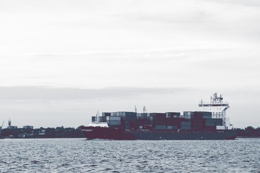 Full container ship moving to Baltic sea. Riga, Latvia