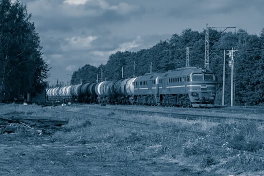 Diesel cargo locomotive with oil tanks in forest