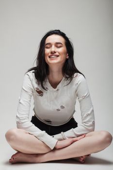 full body shot of beautiful black haired lady sitting on the ground bare feet