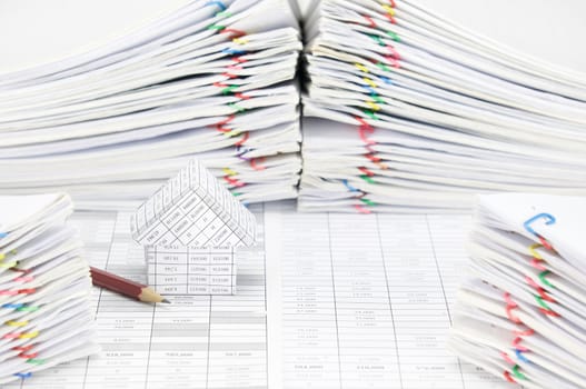 House and pencil on finance account have blur pile overload document of report and receipt with colorful paperclip as foreground and background.