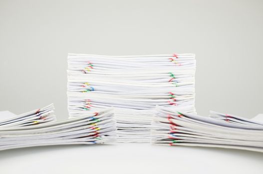 Pile overload document of receipt and report with colorful paperclip have blur pile paperwork around on white table.