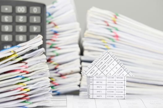 House on finance account have blur pile overload document of report and receipt with colorful paperclip and calculator place vertical as foreground and background.