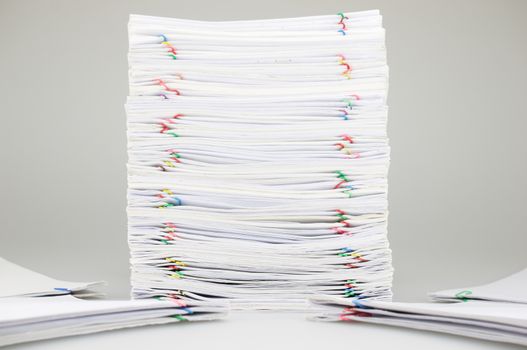 Pile overload paperwork of receipt and report with colorful paperclip have blur pile document around on white table.