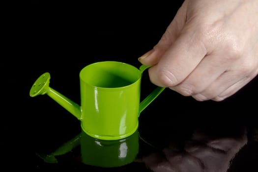 Female hand holding a watering can in front of a chalkboard