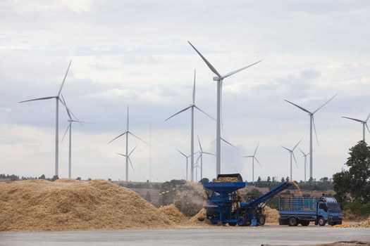  Corn sorting machine is working and Wind power generators in the field against blue sky