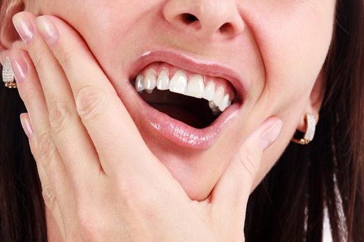 Closeup of woman in strong toothache pain with hands over face. Dental health and care concept.