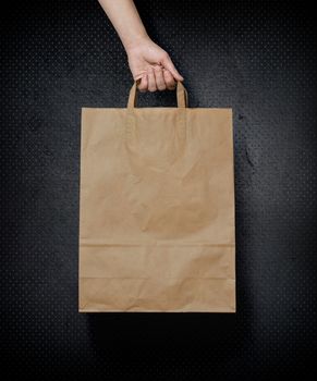 human hand carry blank slate beige paper bag