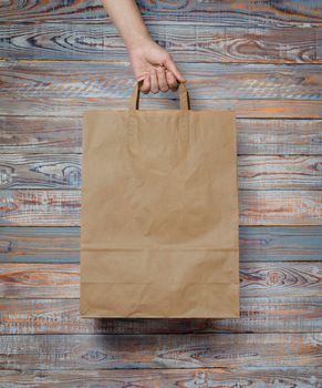 human hand carry blank slate beige paper bag