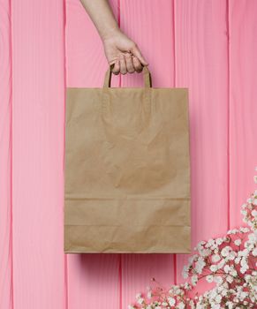 human hand carry blank slate beige paper bag