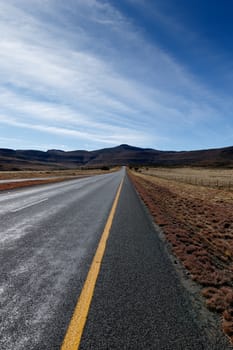 The long road leading to the mountains with blue skies in Graaff-Reinet.