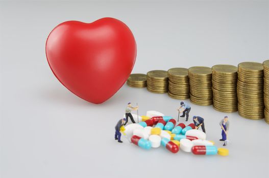 Red heart with gold coins step up stacks and miniature people on white background.