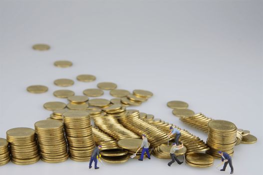 Miniature people are destroyed pile of gold coins on white background.