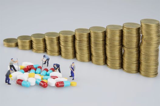 Miniature people are destroyed medicine and pile of coins on white background.