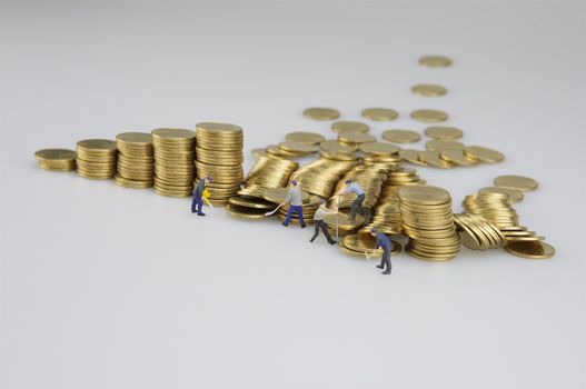 Miniature people are destroyed pile of gold coins on white background.