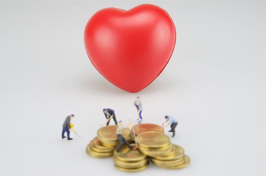 Red heart and blur coin stacks with miniature on white background.on white background.