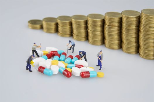 Stack of medicine with miniature people and blur coins on white background.