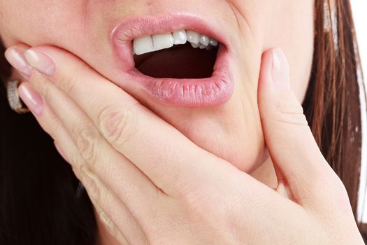 Closeup of woman in strong toothache pain with hands over face. Dental health and care concept.