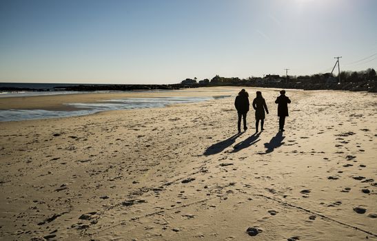 Friends walking at sunset on the beach in Maine, USA