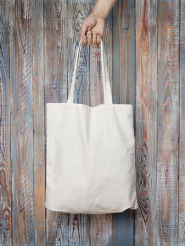 female hand holding a cloth bag on wooden background