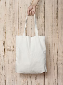 female hand holding a cloth bag on wooden background