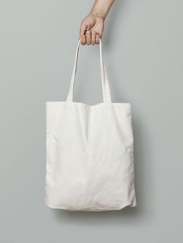 female hand holding a cloth bag on a gray background
