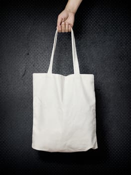 female hand holding a cloth bag on black background