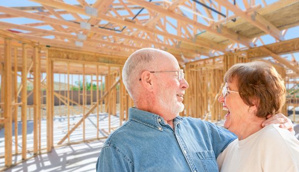 Senior Couple On Site Inside Their New Home Construction Framing.