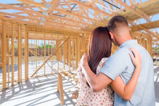 Young Military Couple On Site Inside Their New Home Construction Framing.