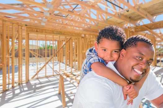 Young African American Father and Mixed Race Son On Site Inside Their New Home Construction Framing.