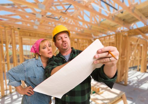 Contractor Showing Plans to Woman On Site Inside New Home Construction Framing.