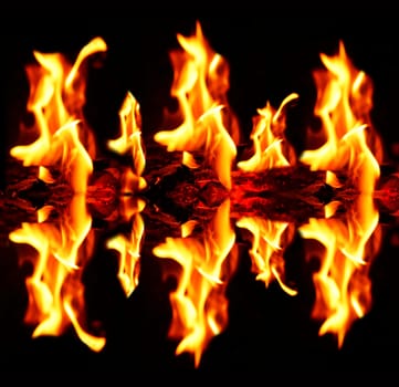 Blazing fire flames with reflection on dark black background.