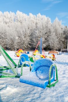 snow covered swing and slide at playground in winter