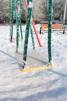 snow covered swing and slide at a playground in winter