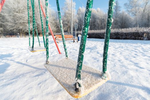 snow covered swing and slide at a playground in winter