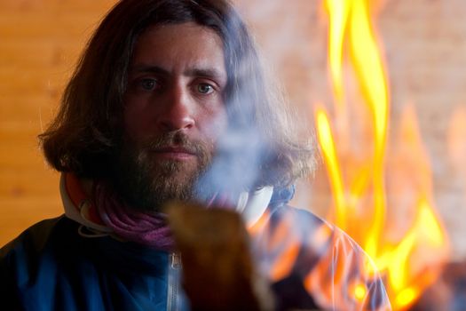 A man with long hair near a fire