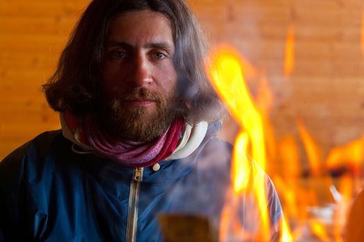 A man with long hair near a fire