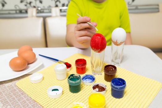 boy paints paints and a brush easter eggs