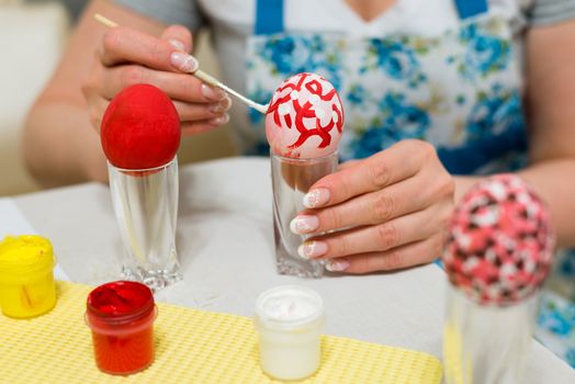 Woman paints the Easter eggs with a brush