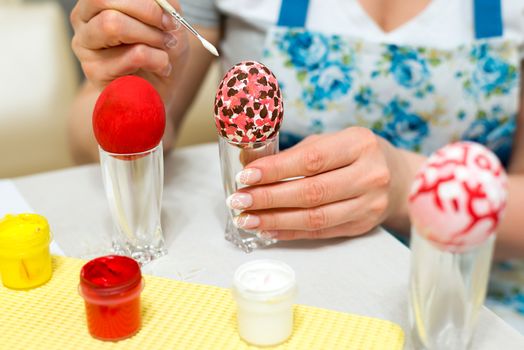 Woman paints the Easter eggs with a brush