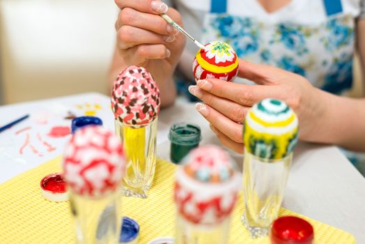 Woman paints the Easter eggs with a brush